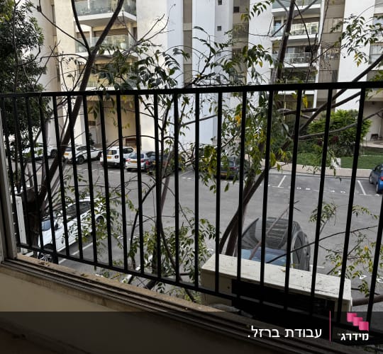 סורג ישר ממתכת בצבע שחור המותקן בחלון דירה